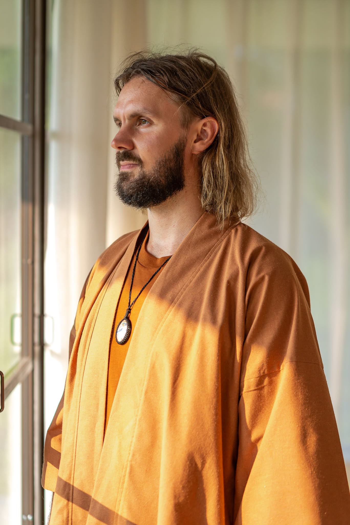 Hardi standing thoughtfully beside a sunlit window